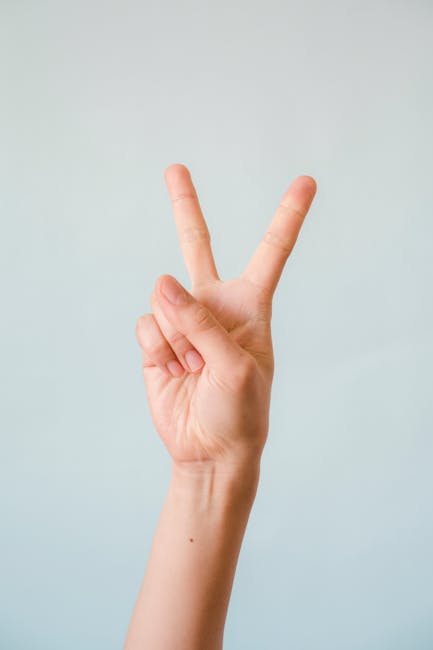 Hand showing a peace sign against a plain background.
