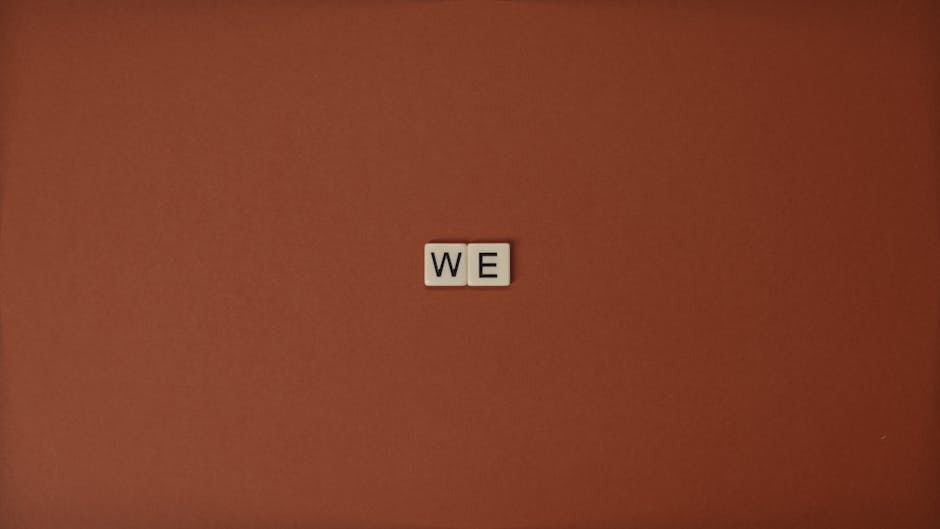 Close-up of Scrabble tiles spelling 'WE' on a brown background, symbolizing unity.