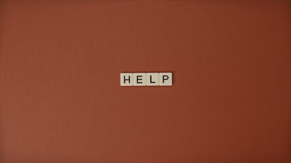 The word 'HELP' spelled with Scrabble tiles on a brown surface, offering conceptual and copyspace.